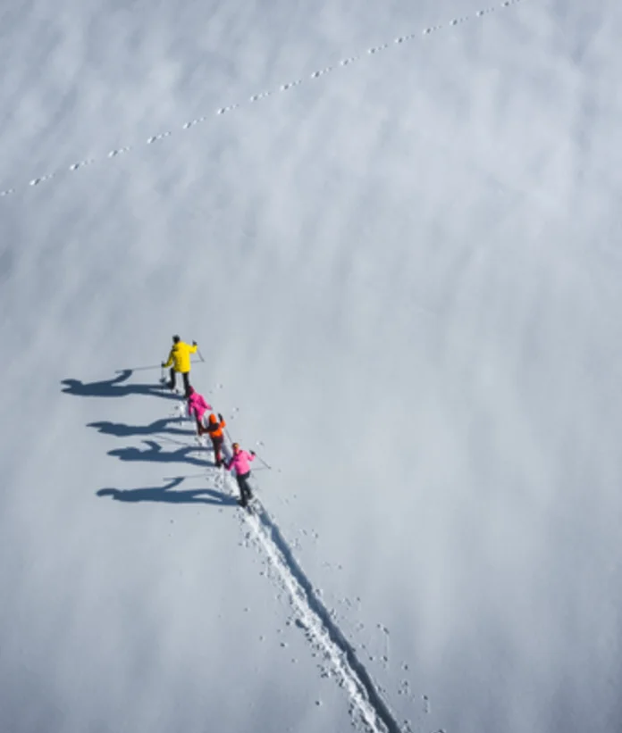 Top view: Family hiking with snowshoes through snow-covered landscape in Wagrain-Kleinarl